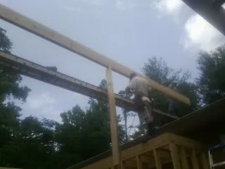 Carpenter setting a ridge beam over a new addition frame — Ice Dam Removal by Roofing Brothers in Beverly