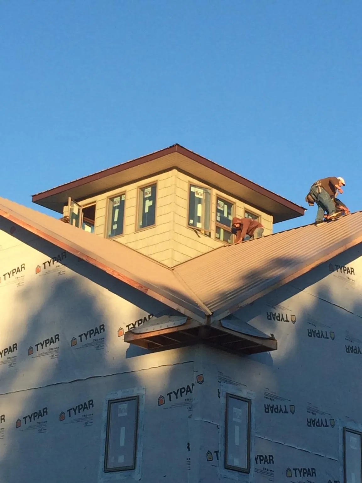 Roofers working around a rooftop cupola on a new metal roof at sunset — Roof Waterproofing in Beverly by Roofing Brothers